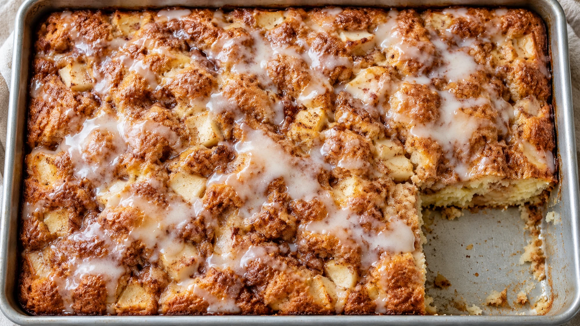 Apple fritter cake in a rectangular pan with one corner served