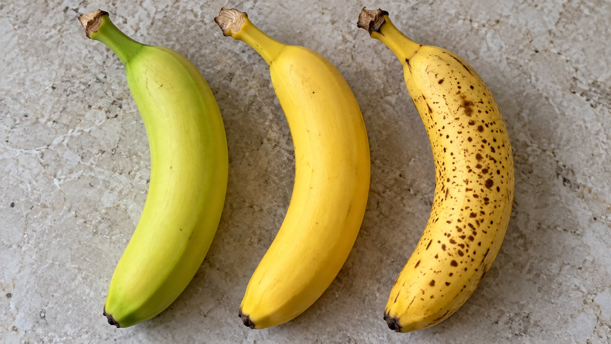 Greenish yellow, yellow and freckled bananas side by side