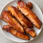 Candied salmon with flaky orange centers on a white plate