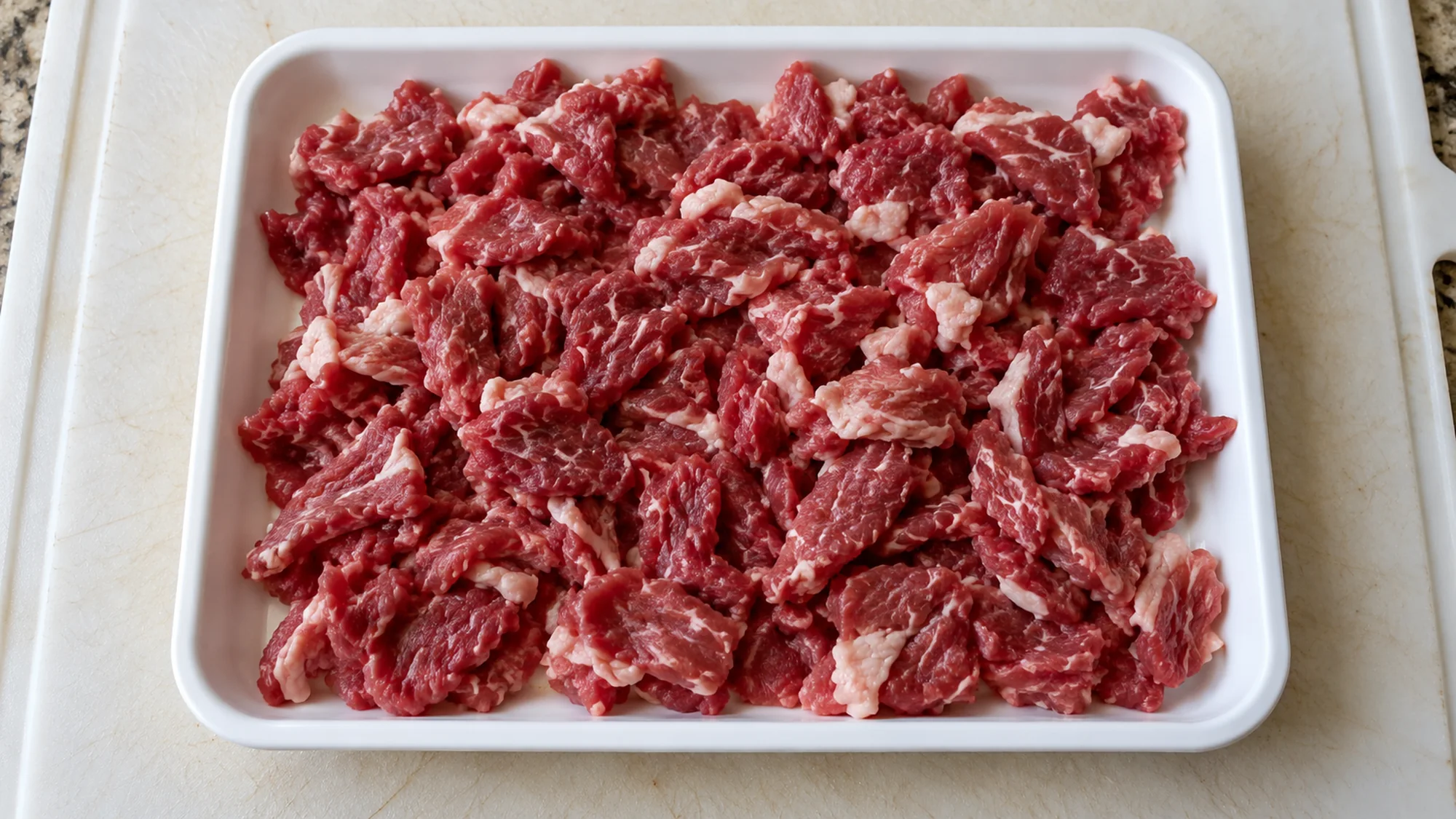 Raw carne picada beef pieces contained in a white preparation tray
