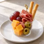 One charcuterie cup with cheese, salami, grapes, olives and breadsticks