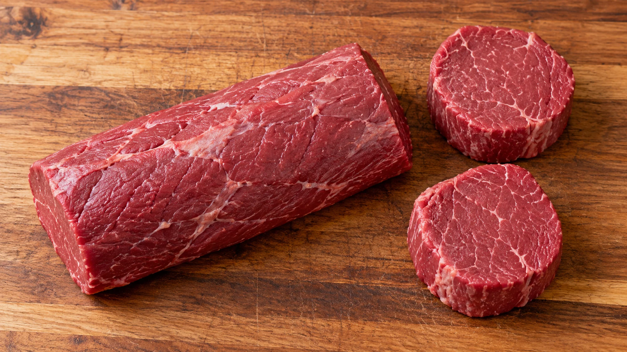 Raw center-cut tenderloin roast beside two individual filet mignon steaks
