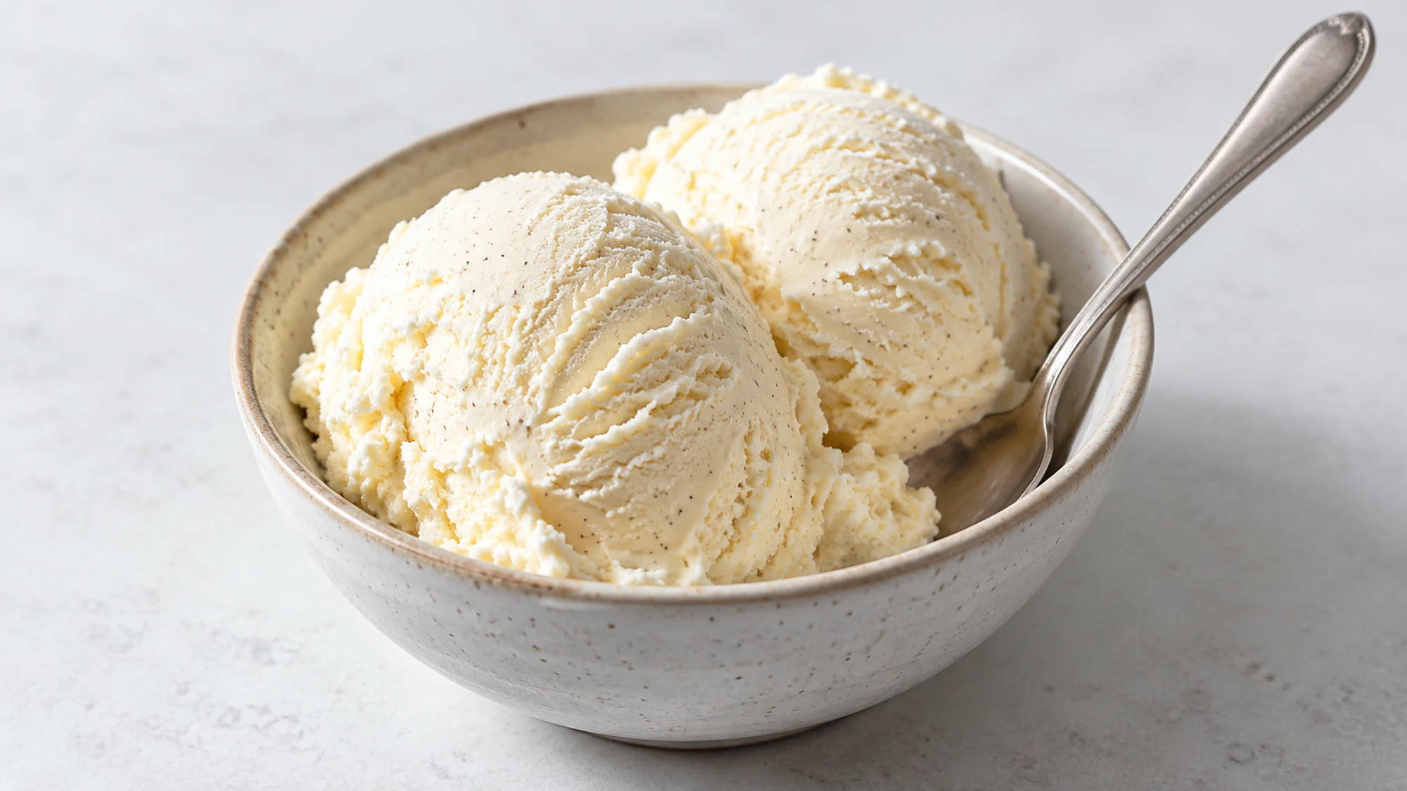 Vanilla ice cream scoops in a bowl with a spoon