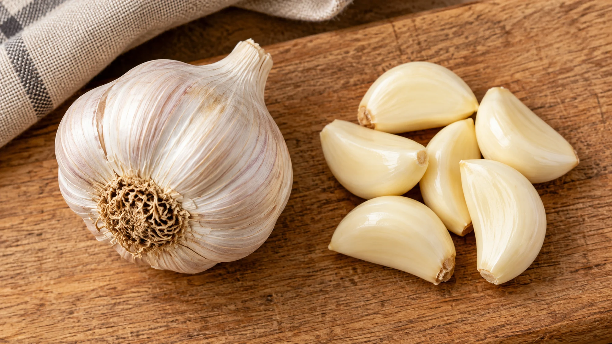 Peeled garlic cloves arranged beside a whole garlic head