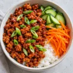 Overhead bowl of gochujang ground chicken, rice, cucumber and carrot