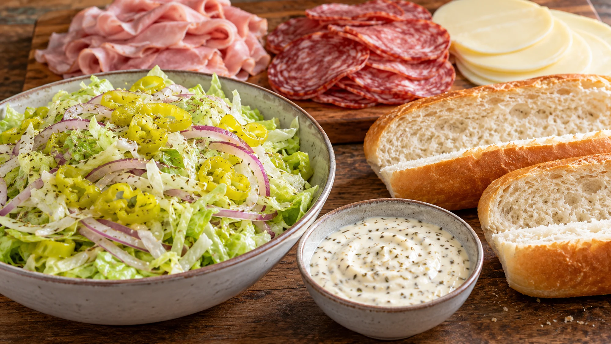 Shredded iceberg lettuce, onion, pepperoncini, and creamy dressing ready for grinder sandwiches