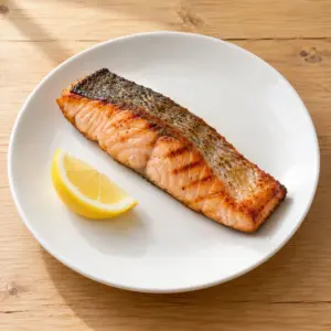 Grilled skin-on salmon fillet with a lemon wedge