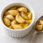 Garlic confit cloves in a small open ramekin with olive oil