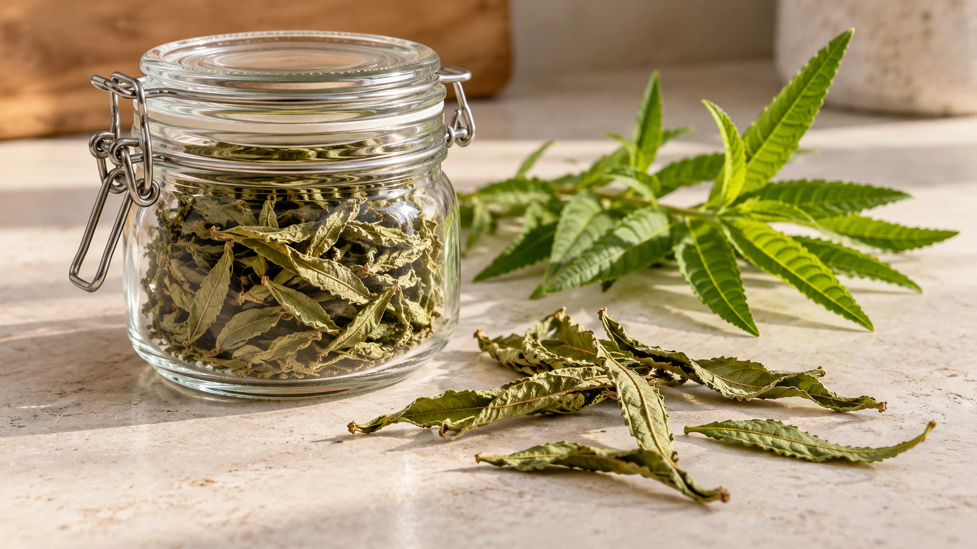 Dried lemon verbena leaves in a sealed glass jar beside a fresh sprig