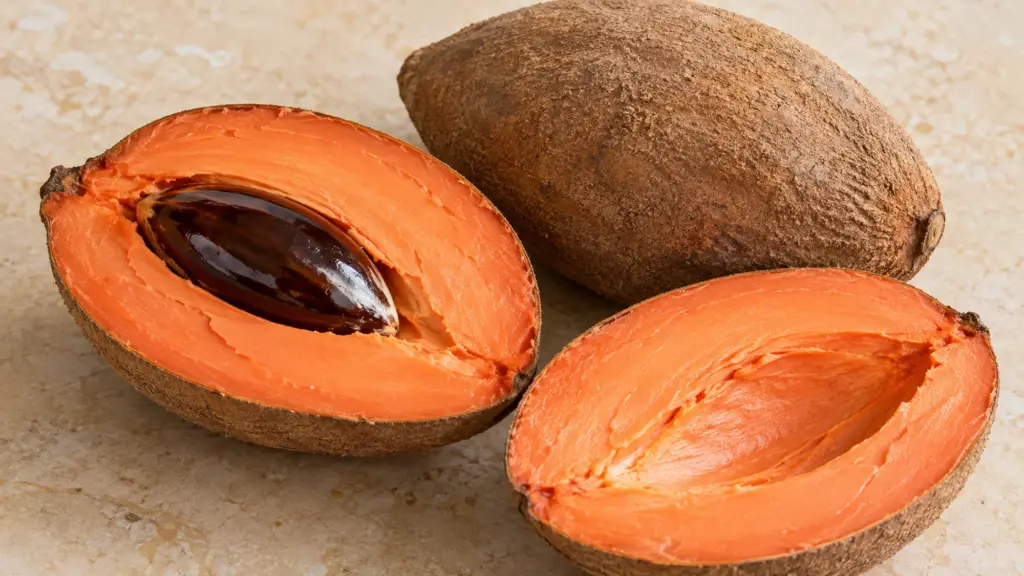 Whole mamey sapote and cut halves showing salmon-orange flesh and a large dark seed