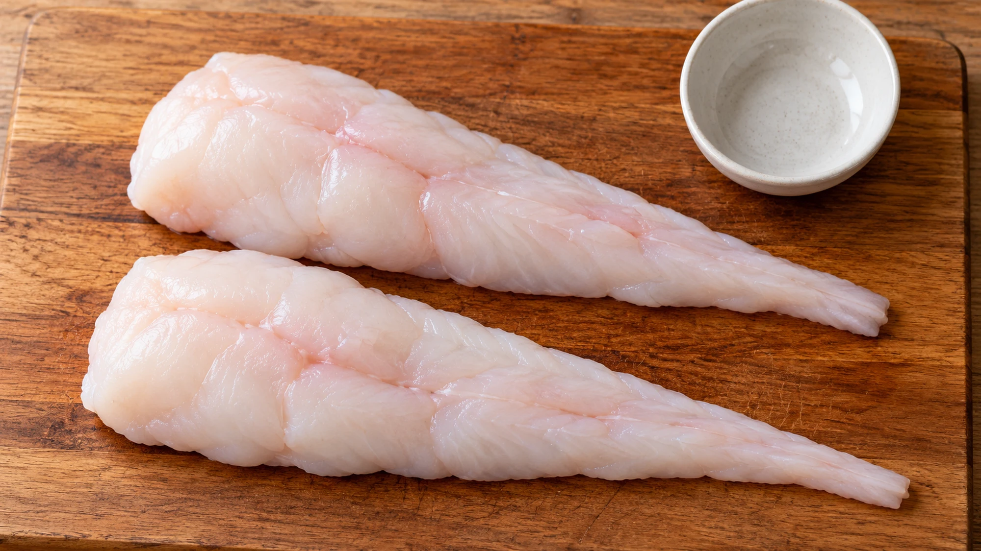 Two pale boneless monkfish tail fillets trimmed of their outer membrane