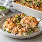 Spoon lifting salmon sushi bake with cooked fish and rice