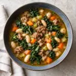 Sausage white bean kale soup in a gray bowl viewed from above