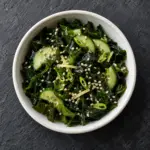 Seaweed salad with cucumber and sesame in a white bowl