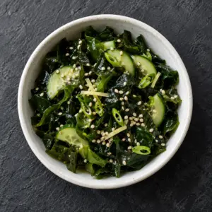 Seaweed salad with cucumber and sesame in a white bowl