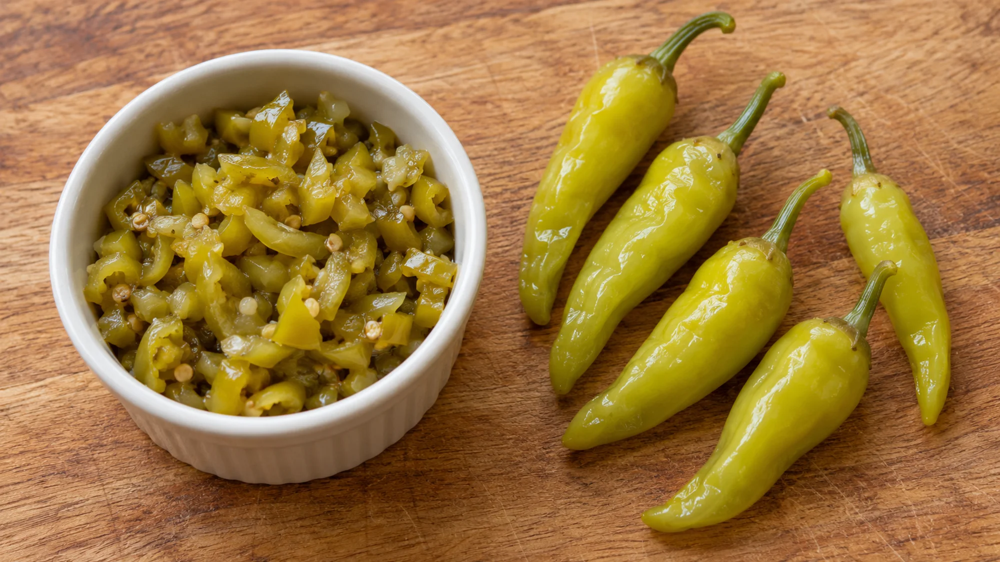 Chopped sport peppers in a ramekin beside whole peppers